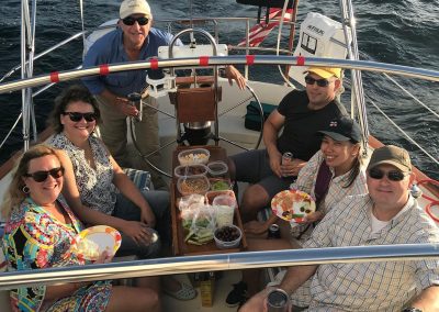 7 people eating on a sailboat