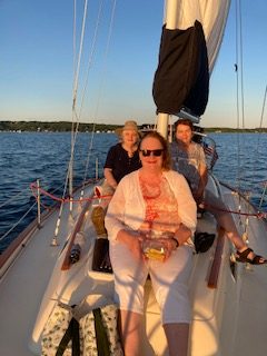 Three people smiling on sailboat on 2nd Wind sailboat on grand traverse bay in Traverse City, Michigan with WIND Sailing.