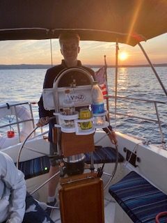Man taking the helm on a sunset sail on 2nd Wind sailboat on grand traverse bay in Traverse City, Michigan with WIND Sailing.