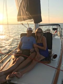 Two people on sailboat at sunset on 2nd Wind sailboat on grand traverse bay in Traverse City, Michigan with WIND Sailing.